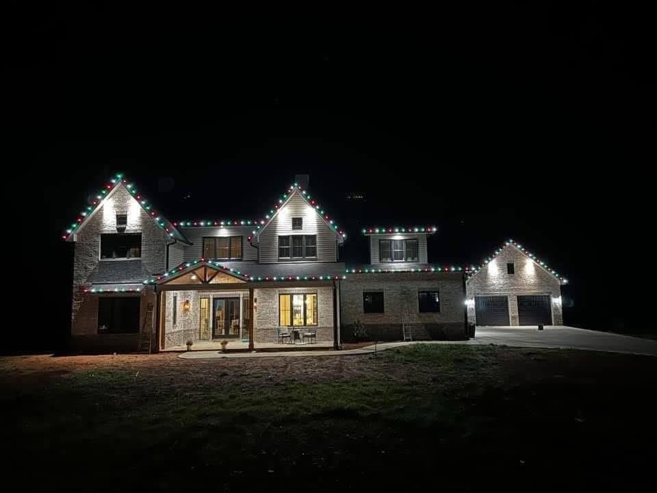 Large Cincinnati home with red and green roofline lighting and a lit front porch at night